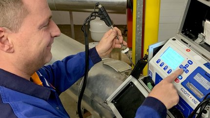 Ein Techniker bedient ein Messgerät, während er einen Sensor in der anderen Hand hält, um Daten zu erfassen.