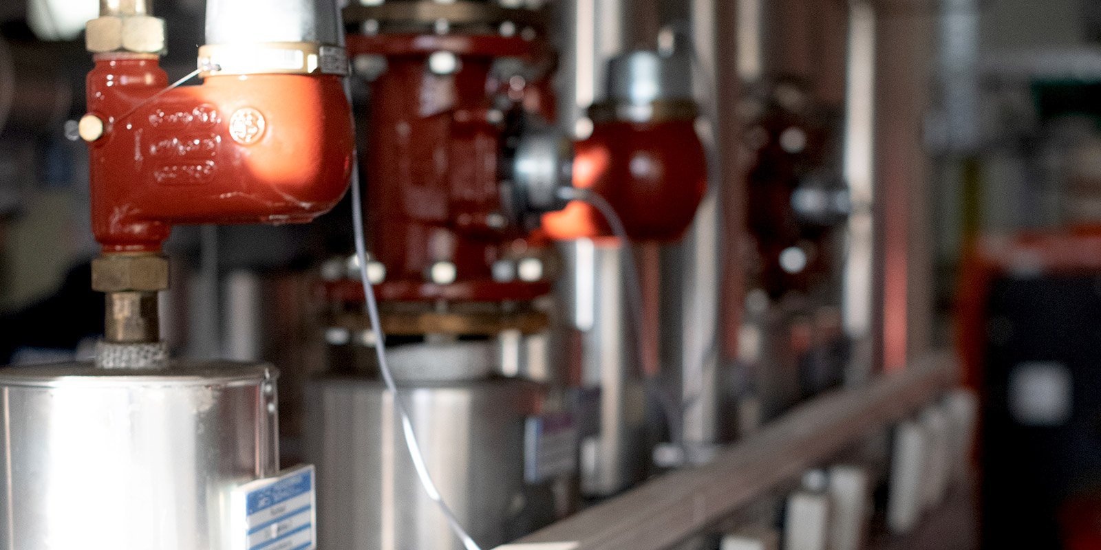 Eine Reihe von glänzenden Metallrohren mit roten Ventilen, die in einer industriellen Umgebung installiert sind.