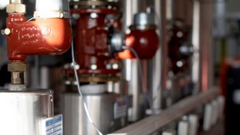 Eine Reihe von glänzenden Metallrohren mit roten Ventilen, die in einer industriellen Umgebung installiert sind.