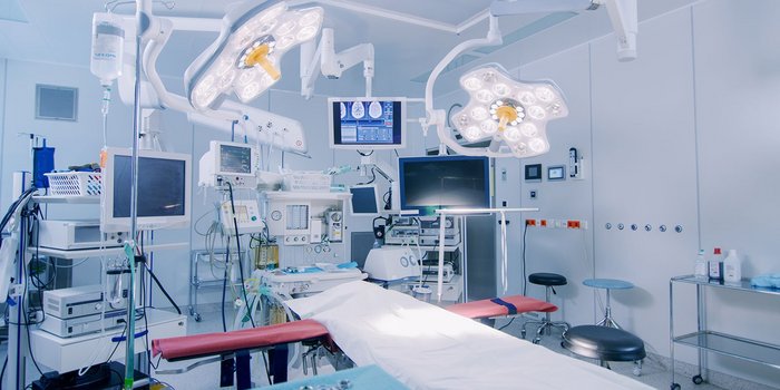 Ein moderner Operationssaal mit mehreren Monitoren, chirurgischen Lampen und einem vorbereiteten OP-Tisch, der mit einem weißen Tuch bedeckt ist.