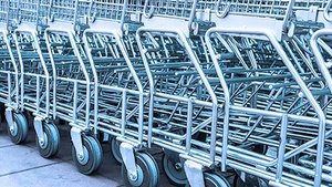 Eine Reihe von Einkaufswagen steht ordentlich auf einem Gehweg, ihre silbernen Rahmen glänzen im Licht.