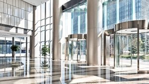Ein heller, moderner Eingangsbereich mit großen Fenstern und glänzendem Boden, umgeben von Pflanzen und Glastüren.