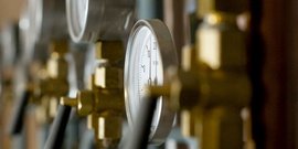 Mehrere Druckanzeigen mit weißen Ziffern und goldenen Armaturen, die präzise Messungen in einer Werkstatt darstellen.